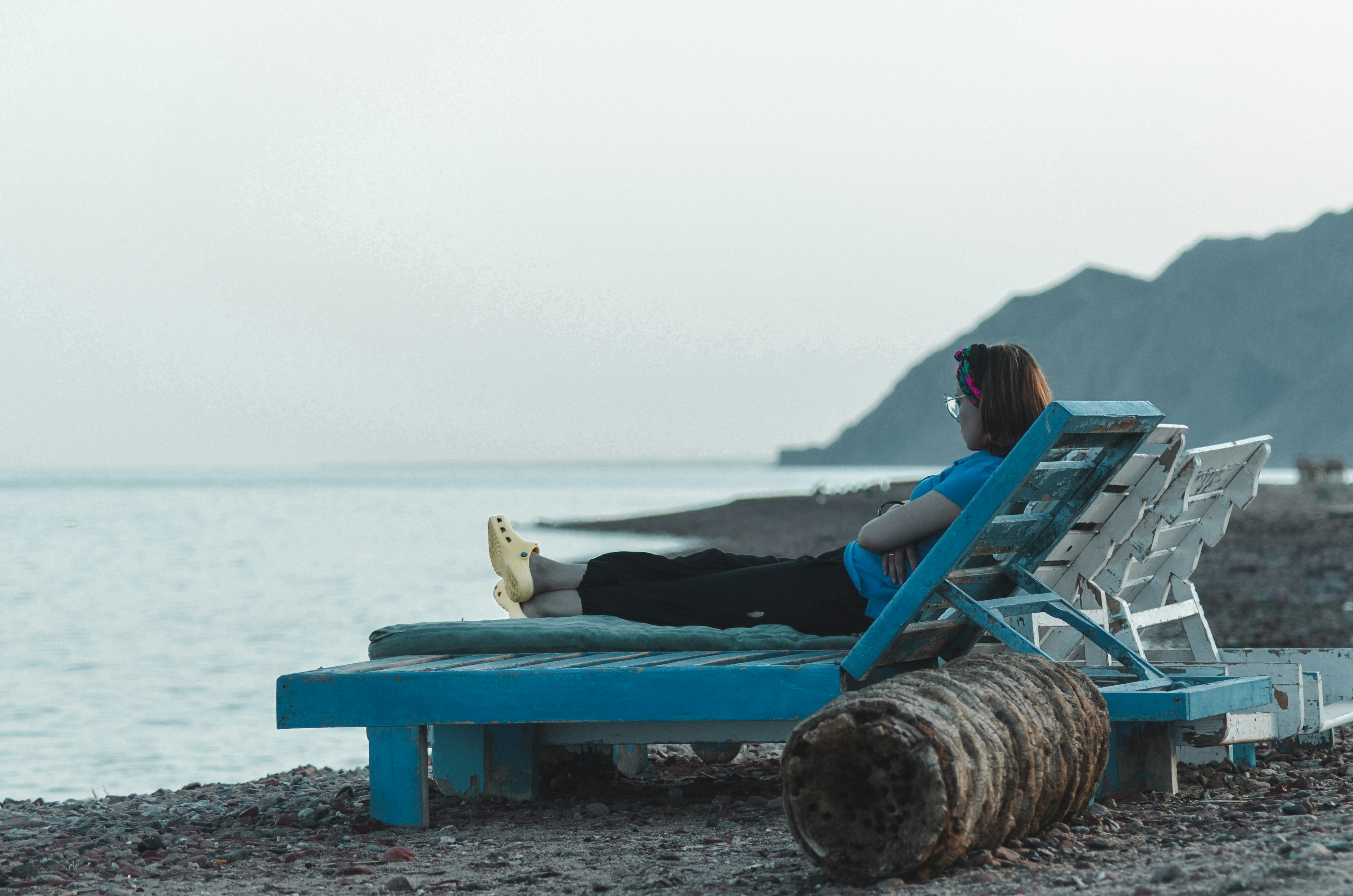 woman sitting on beach chair near mountain during daytime